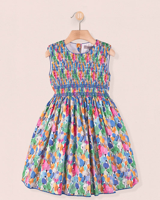 Front view of the Amandine Liberty Tulip Fields Blue Smock dress, a sleeveless cotton dress with a hand-smocked bodice and full skirt in a multicolor tulip Liberty print hanging on a hanger.