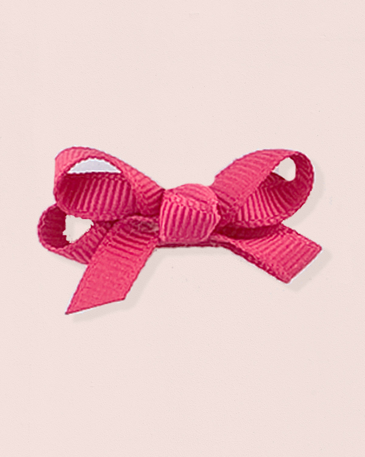 Close-up of a single fuchsia grosgrain baby hairbow attached to velcro, displayed against a light pink 