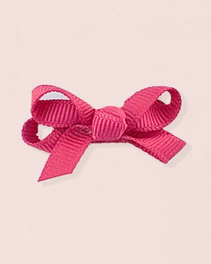 Close-up of a single fuchsia grosgrain baby hairbow attached to velcro, displayed against a light pink 