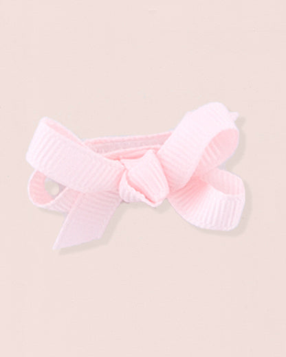 Close-up of a single pink grosgrain baby hairbow attached to velcro, displayed against a light pink 