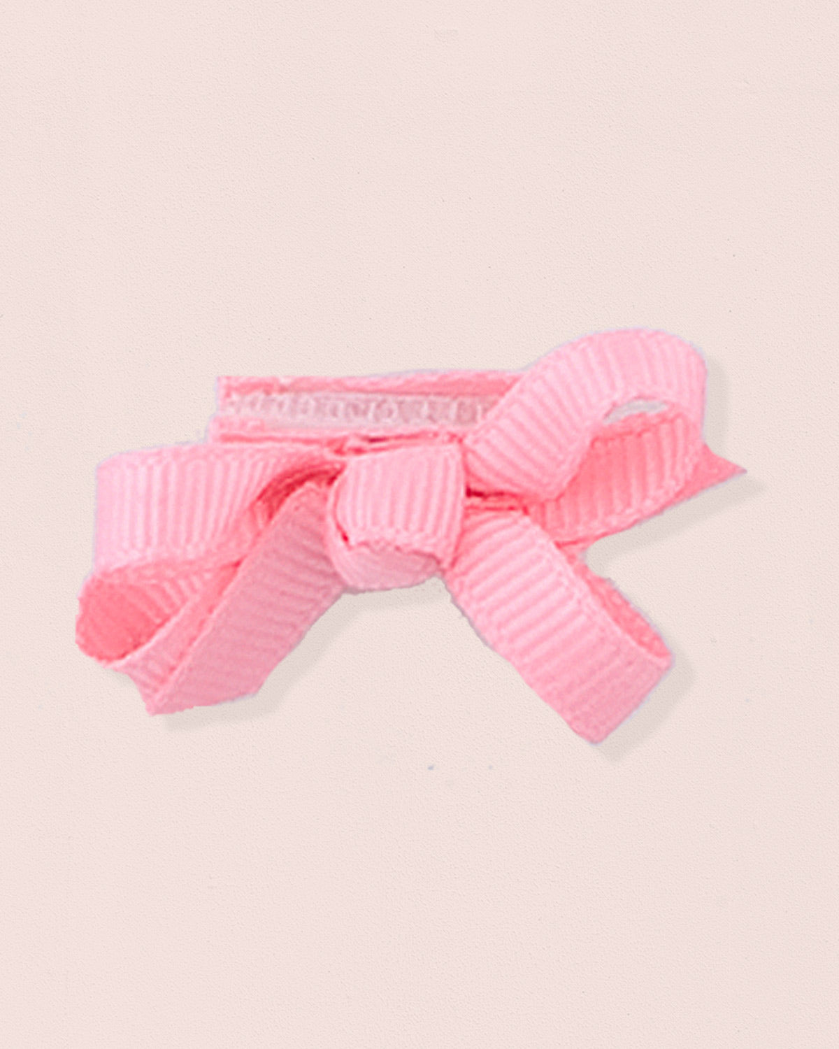 Close-up of a single rose grosgrain baby hairbow attached to velcro, displayed against a light pink 