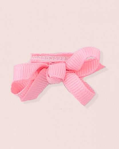 Close-up of a single rose grosgrain baby hairbow attached to velcro, displayed against a light pink 