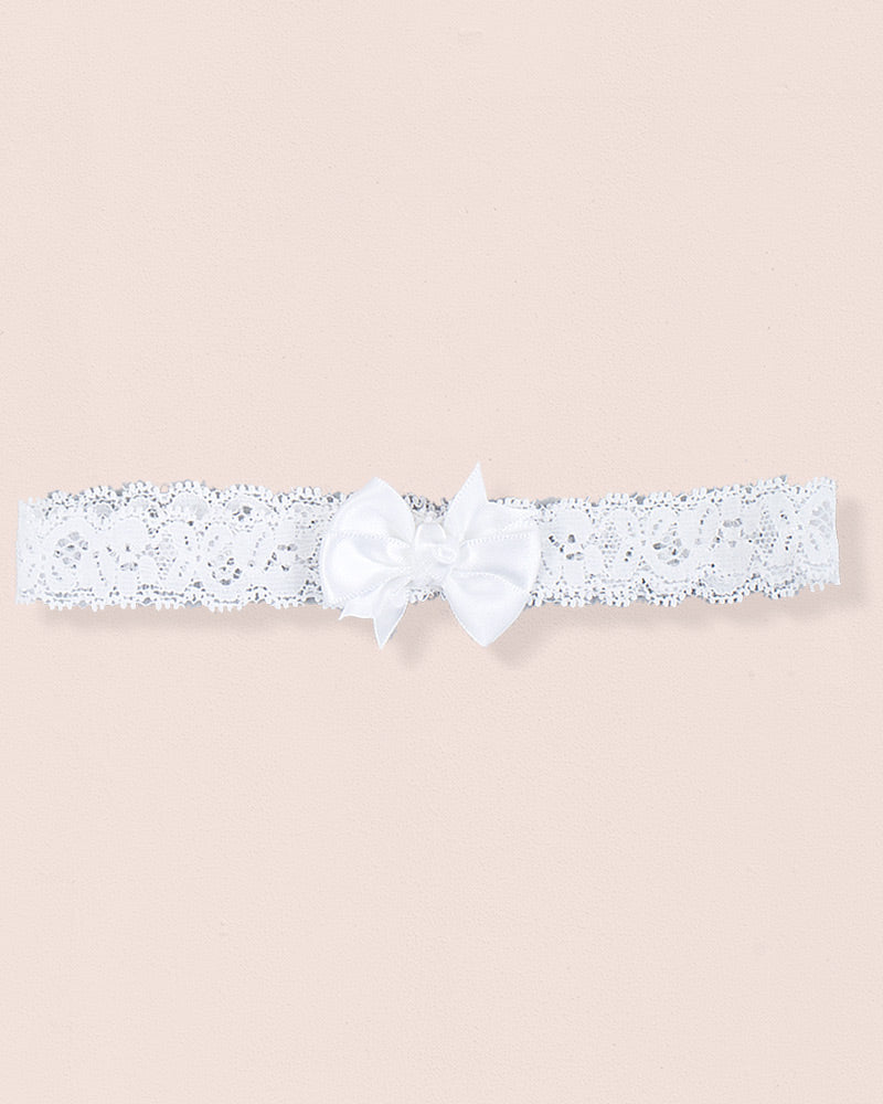 White baby headband made of lace with a centered satin bow displayed on a neutral background